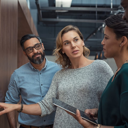 Multiethnic business people discussing charts and graphs showing the results of their successful teamwork. Mature business woman showing presentation to casual colleagues in during night meeting.